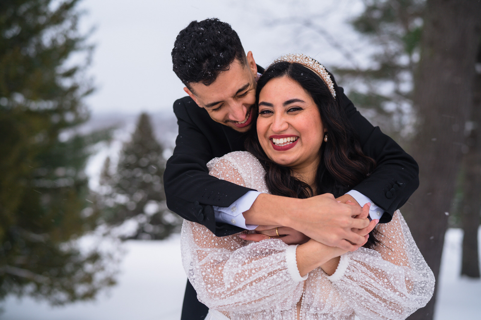 couple hugging each others in the snow. They are smiling and laughing