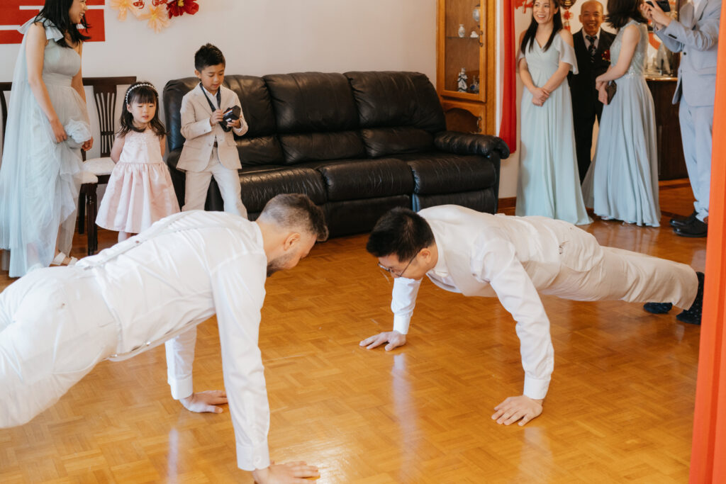 Groom and his brother in law doing 100 push ups in the living room at a chinese wedding in Montreal