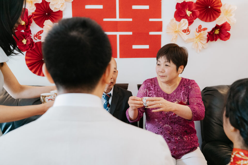 Groom serving tea to his mother in law during the tea ceremony of a chinese wedding in montreal