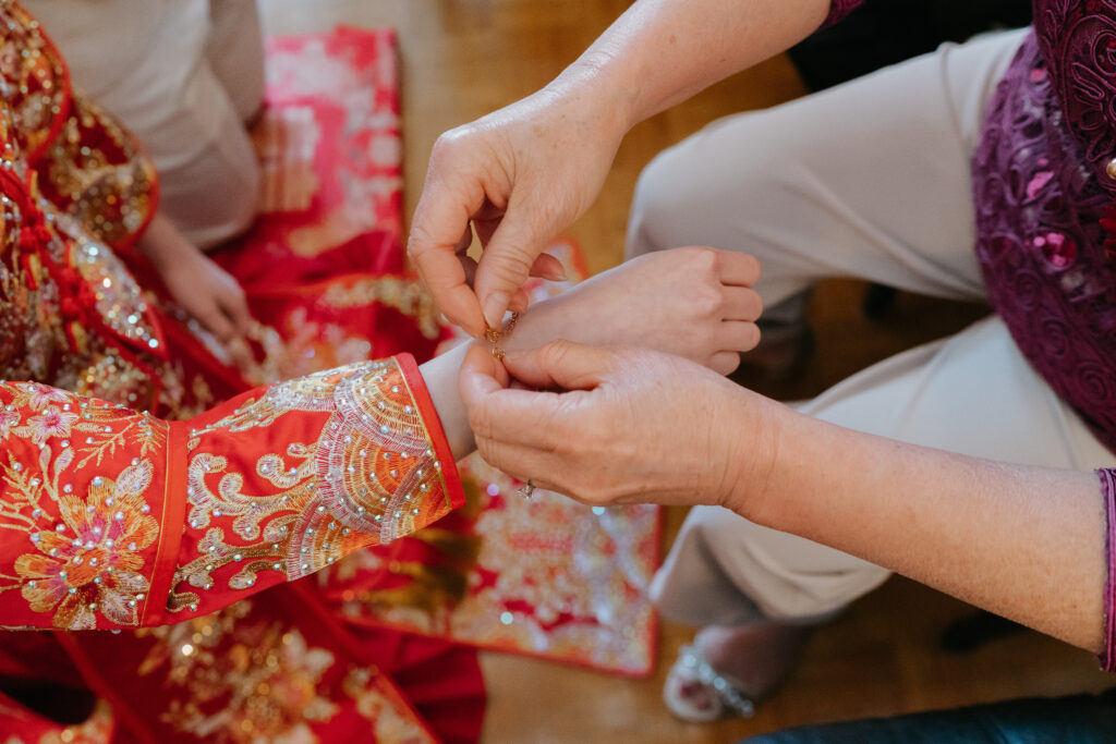close up of the bride's mom putting a bracelet on her wrist